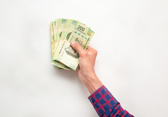 Mano de un hombre joven sosteniendo varios billetes de doscientos pesos mexicanos sobre un fondo...