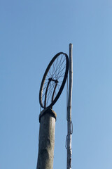 Old village well.  Lifting mechanism from a bicycle wheel.  Against the background of the blue sky.
