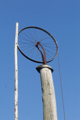 Old village well.  Lifting mechanism from a bicycle wheel.  Against the background of the blue sky.