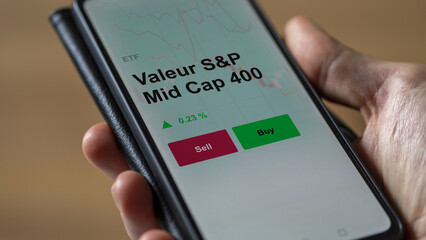 Un investisseur analyse un fonds etf valeur s&p mid cap 400 sur un graphique. Un téléphone affiche le cours de l'ETF. Texte en français francais Valeur S&P Mid Cap 400