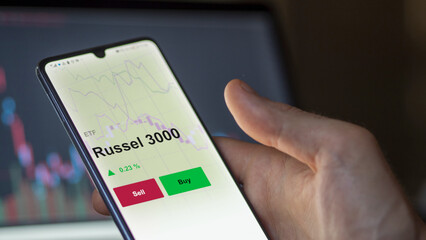 Un investisseur analyse un fonds etf russel 3000 sur un graphique. Un téléphone affiche le cours de l'ETF. Texte en français francais Russel 3000