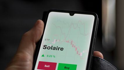 Un investisseur analyse un fonds etf solaire sur un graphique. Un téléphone affiche le cours de...