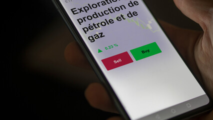 Un investisseur analyse un fonds etf exploration et production de pétrole et de gaz sur un graphique. Un téléphone affiche le cours de l'ETF. Texte en français francais.