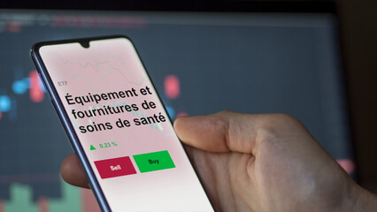 Un investisseur analyse un fonds etf équipement et fournitures de soins de santé sur un graphique. Un téléphone affiche le cours de l'ETF. Texte en français francais.
