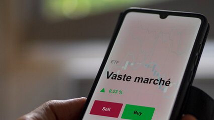 Un investisseur analyse un fonds etf vaste marché sur un graphique. Un téléphone affiche le cours de l'ETF. Texte en français francais Vaste marché