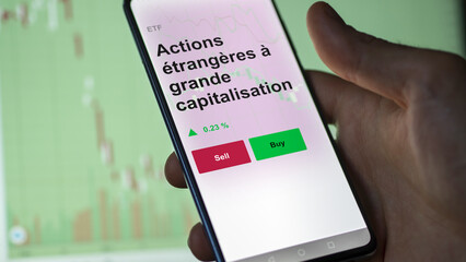 Un investisseur analyse un fonds etf actions étrangères à grande capitalisation sur un graphique. Un téléphone affiche le cours de l'ETF. Texte en français francais