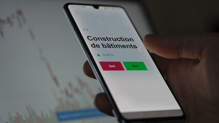 Un investisseur analyse un fonds etf construction de bâtiments sur un graphique. Un téléphone affiche le cours de l'ETF. Texte en français francais Construction de bâtiments