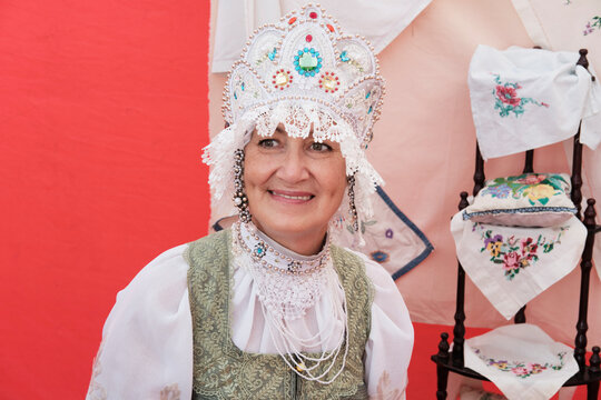 Portrait of smiling senior woman in stylized ancient Russian headdress - kokoshnik at rural holiday.