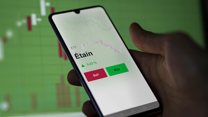 Un investisseur analyse un fonds etf étain sur un graphique. Un téléphone affiche le cours de l'ETF. Texte en français francais Étain