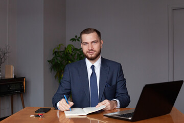 Handsome young businessman working at laptop in office.