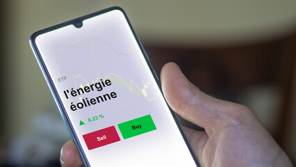 Un investisseur analyse un fonds etf l'énergie éolienne sur un graphique. Un téléphone affiche le cours de l'ETF vent. Texte en français, francais. 