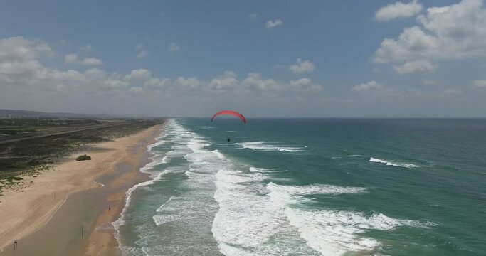 Powered Paraglide flying above a sunny beach.