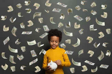Serious smart little boy on falling us dollar money rain on black background