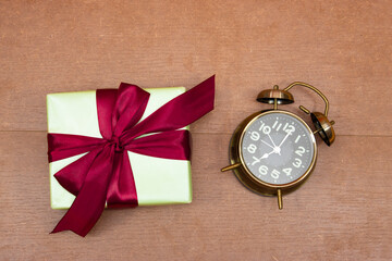 Gift box with alarm clock over wood table
