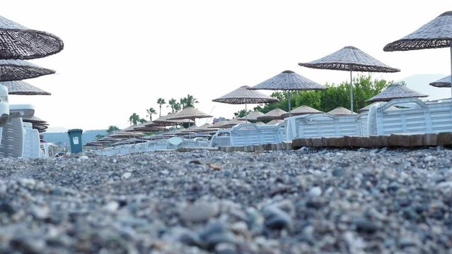 beach with umbrellas. Girls walk along the city beach in Camyuva in search of an empty seat on a sun lounger. Sunset evening on the beach. Summer evening at the sea. Walkway across the beach.