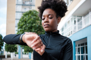 A fitness black young woman is looking at her smart watch.