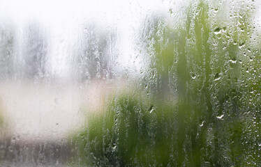 Heavy rain. Raindrops on the window glass on a summer day. Selective focus, shallow depth of field....