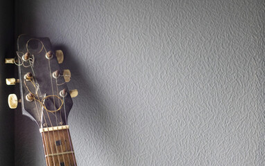 An acoustic old guitar in dust stands against a gray wall with copy space. Background for a...