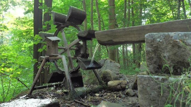 The water mill under the wooden trough is turned by the force of the falling water.