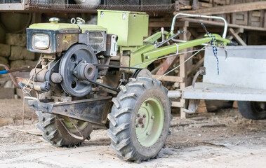 Typical heavy diesel walking tractor with trailer. Agricultural transport equipment of the countryside. Portable agricultural equipment, walking minitractor. The start system is mechanical and manual.