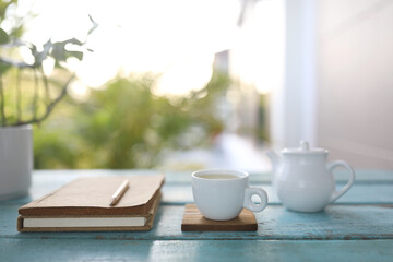 White tea cup and vintage tea pot and small plants on wooden table