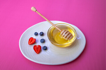 Strawberries with blueberries and honey and a wooden spoon for honey 