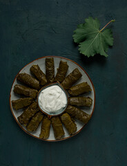 Dolma, cabbage rolls in grape leaves, Traditional Armenian dish, with white sauce, top view, close-up, selective focus,
