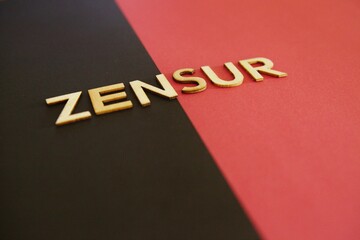 Zensur Buchstaben schraeg auf dunklem und roten Hintergrund