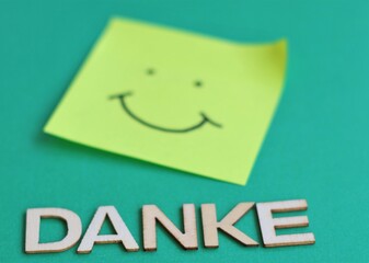 Danke Postit Smiley auf Gruenen Hintergrund mit dem Wort Danke