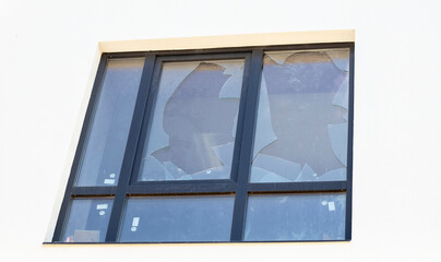 Broken window of a residential building, sharp pieces of glass sticking out. Fighting in Ukraine, the destruction of buildings from bombing and rocket attacks by a blast wave.