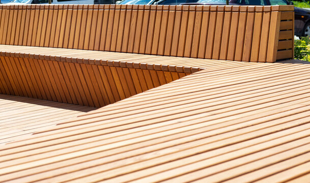New modern park bench. Outdoor urban architecture outdoors, urban public furniture. An empty board seat without people, a comfortable bench in the recreation area.