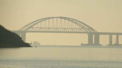View of the bridge over the river with passing ships. Shot. Timelapse. Movement of shipping ships on the river in the early morning