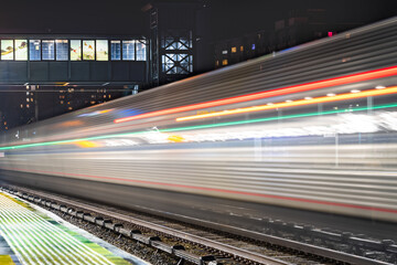 Fototapeta na wymiar Moving passenger train through railway station platform at night. Blurred train car and lights.