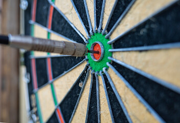 a dart stuck in the center of a dartboard on a wooden wall