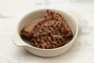 fresh grilled hamburgers in small bowl on ceramic