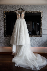 Fototapeta na wymiar Wedding dress hanging on the mirror in the room