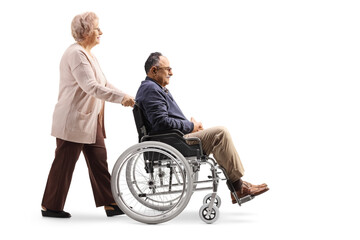 Elderly woman pushing a mature man in a wheelchair