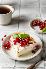 Homemade cottage cheese casserole garnished with sauce, redcurrant and cup of coffee on gray tile background