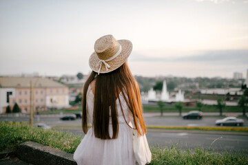 Portrait of a relaxed woman with hat looking forward at the horizon cityscape in the background copy space - 520256574
