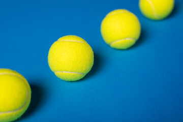 New tennis balls inline on blue background with copy space. 