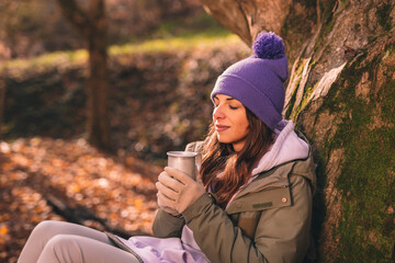 Woman drinking hot tea while taking hiking break