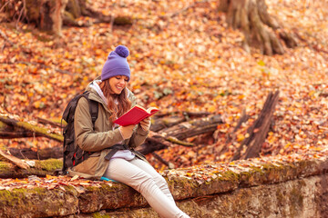 Woman reading a book in the forest while taking a hiking break