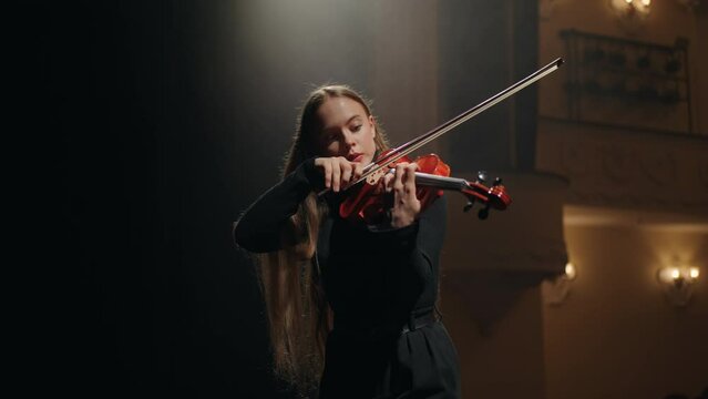 female violin player is practicing to play violin in music school, portrait of female violinist in music hall