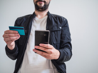 Caucasian man buying through smartphone and with credit card in hand