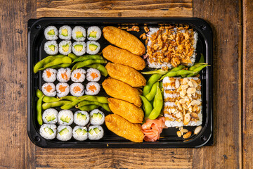  Sushi black plate on wood table, top view.