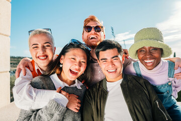 Five multi-ethnic friends posing for a photo smiling and having fun outdoor.