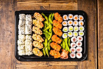  Sushi black plate on wood table, top view.