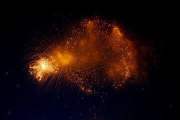 Bright orange glowing fireworks with sparks flying sideways against the night sky. High quality photo