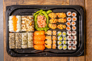  Sushi black plate on wood table, top view.