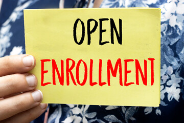 closeup woman holding a yellow card with open enrollment 